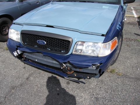 1991 Ford LTD Crown Victoria - A damaged Ford Crown Victoria is parked next to another vehicle, showing significant front-end damage.