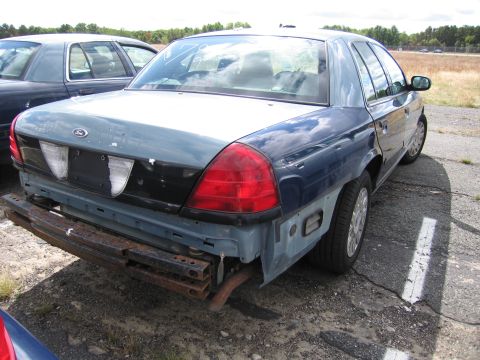 1991 Ford LTD Crown Victoria - Rear view of a Ford Crown Victoria, showing damage and missing bumper components. Another vehicle is visible in the background.