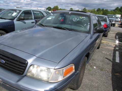 1991 Ford LTD Crown Victoria - A blue Ford Crown Victoria is parked in a lot with other vehicles under a cloudy sky.