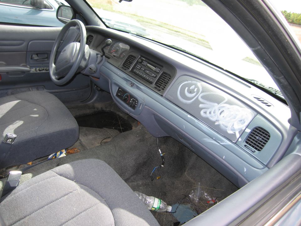 Interior view of a 1991 Ford Crown Victoria LTD showing the dashboard with graffiti, steering wheel, and seats