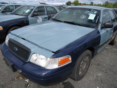 1991 Ford LTD Crown Victoria - Two-tone Ford Crown Victoria police cars parked in a lot, one with "STATE POLICE 1282" visible on the fender.