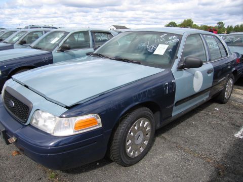 1991 Ford LTD Crown Victoria - A two-tone police car is parked in a lot with other similar vehicles. Text on the fender reads "STATE POLICE".