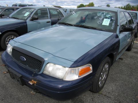 1991 Ford LTD Crown Victoria - A two-tone Ford Crown Victoria is parked in a lot with other vehicles under a cloudy sky.