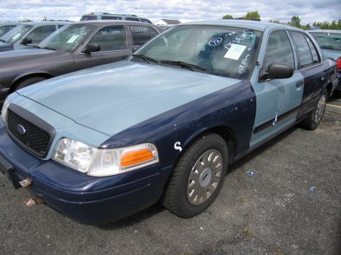 1991 Ford LTD Crown Victoria - This two-tone police car is seen from the front quarter angle, with visible markings on the windshield.
