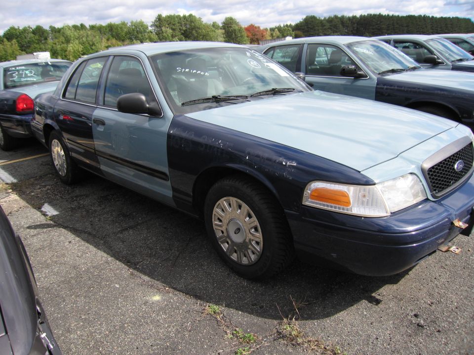 Ford Crown Victoria with two-tone paint, light blue hood and fenders, dark blue doors and rear. Parked in lot with other cars