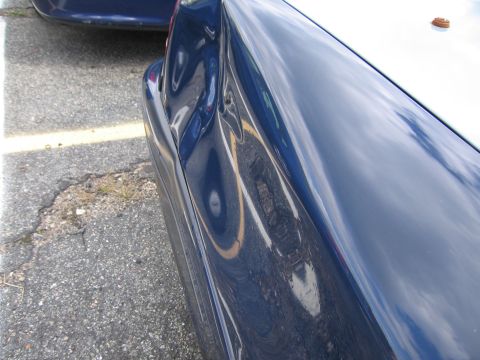 1991 Ford LTD Crown Victoria - A dented blue car fender is visible, with another blue vehicle in the background.