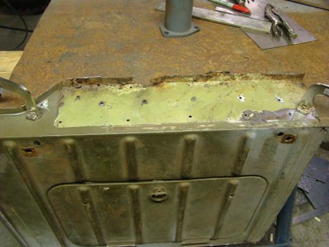 1948 Jeep Wrangler - Close-up view of a corroded metal panel, possibly from a vehicle's undercarriage, undergoing repair.