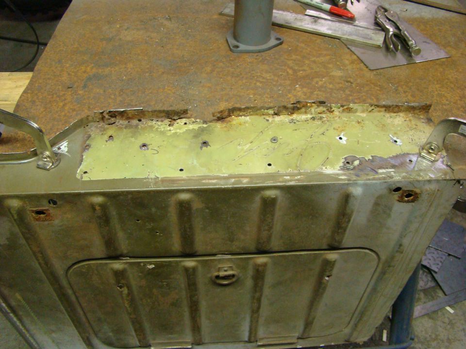 Rusted metal panel with rivets and a latch, showing signs of repair and wear