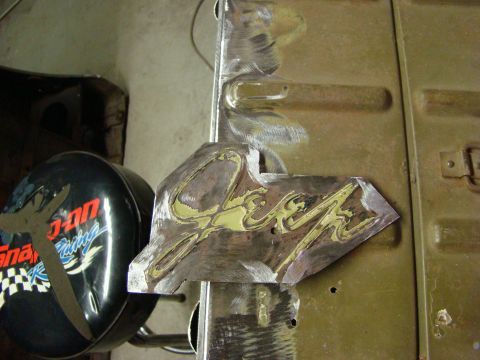 1948 Jeep Wrangler - A metal emblem with yellow lettering is shown, with evidence of recent work and a racing-themed item nearby.