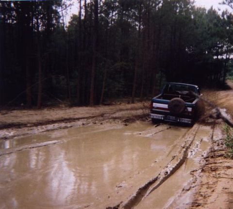 1989 Ford Bronco - This 1989 Ford Bronco navigates a muddy trail, kicking up water and dirt.