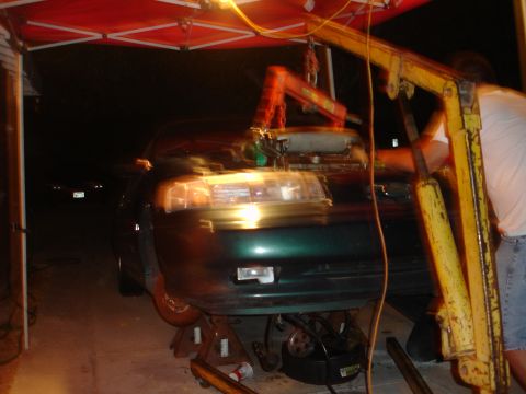1993 Ford Taurus - A 1993 Ford Taurus is shown from the front as its engine is being removed using an engine hoist.