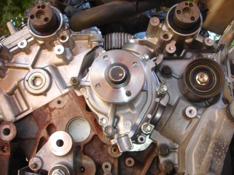 1993 Ford Taurus - Detailed view of engine components including a water pump, timing gears, and a tensioner pulley, showing signs of wear and rust.