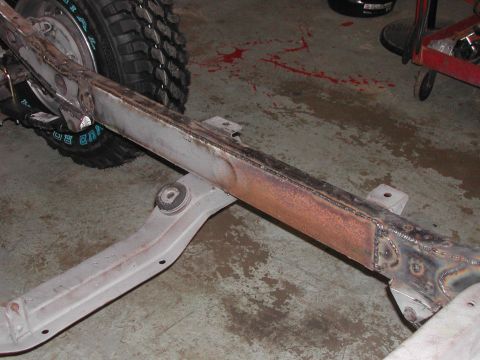 1948 Jeep Wrangler - A close-up view of a vehicle's frame and a tire, showing some rust and repair work.