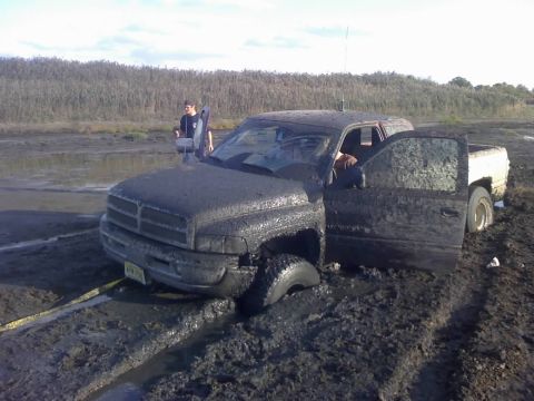 1996 Dodge 1500 - Mud-covered 1996 Dodge 1500 stuck in a muddy field with the driver's door open.