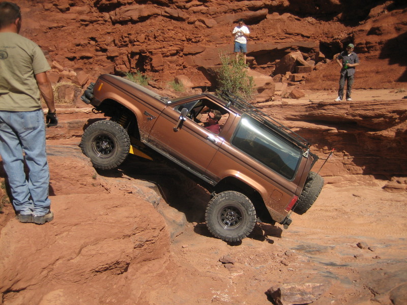 Brown 1986 Ford Bronco II climbing a rocky trail, 3/4 front view