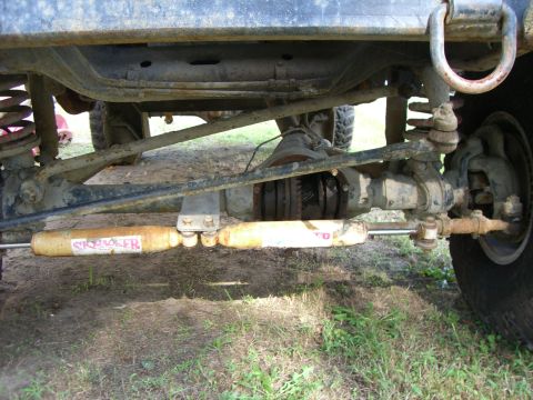 1988 Ford Bronco - Underside view of a lifted 4x4 front solid axle shot from ground level, showing the open differential housing with the ring gear visible, c…