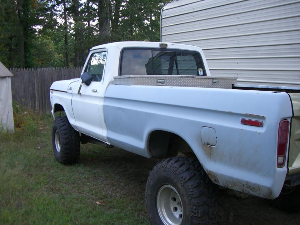 White and gray Ford pickup truck with large tires, seen from the side