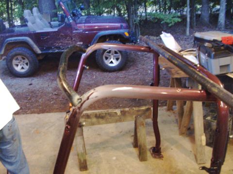 1995 Ford Bronco - A Jeep roll cage is being worked on, with a red Jeep visible in the background.