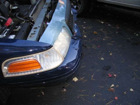 1991 Ford LTD Crown Victoria - The front of a dark blue vehicle, possibly a 1990s sedan, is visible with damage to the bumper and hood.