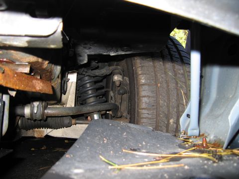 1991 Ford LTD Crown Victoria - Close-up view of a vehicle's undercarriage, revealing suspension parts and a tire.
