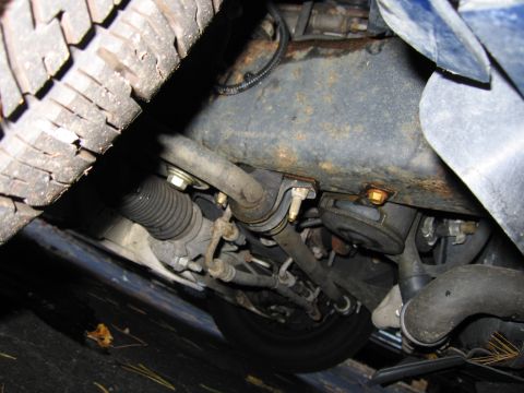 1991 Ford LTD Crown Victoria - Close-up view of a vehicle's undercarriage, revealing steering and suspension components with signs of wear and rust.