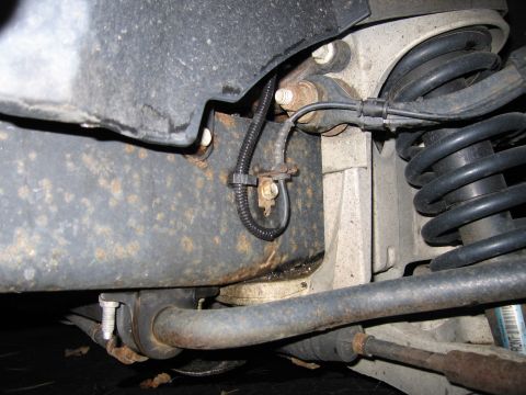 1991 Ford LTD Crown Victoria - Close-up view of the front suspension system, showing various metal components and a black wiring harness.