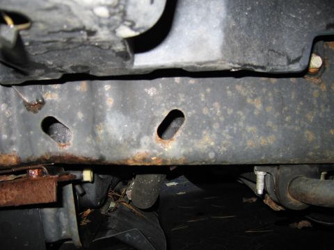 1991 Ford LTD Crown Victoria - Underside view of a heavily rusted vehicle frame, showing structural components and corrosion.