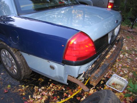 1991 Ford LTD Crown Victoria - This vehicle shows significant damage to its rear, including a missing bumper and exposed exhaust pipe.