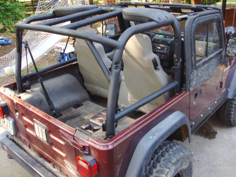 1995 Ford Bronco - This maroon Jeep Wrangler features an aftermarket roll cage and is viewed from the rear passenger side.