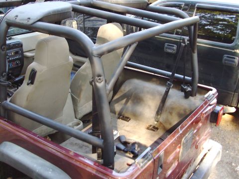 1995 Ford Bronco - Jeep interior with aftermarket roll cage installed. A second vehicle is visible in the background.
