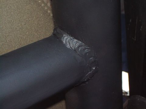 1995 Ford Bronco - Close-up of a welded metal tube, part of a larger structure, with visible weld beads and a textured fabric background.