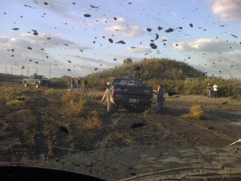 1996 Dodge 1500 - Several trucks are stuck in a muddy area, with people observing the situation. Mud is flying through the air.