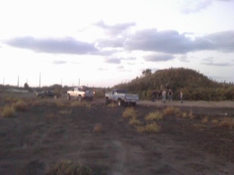 1996 Dodge 1500 - Multiple vehicles and people gathered on a dirt road with a large hill in the background.