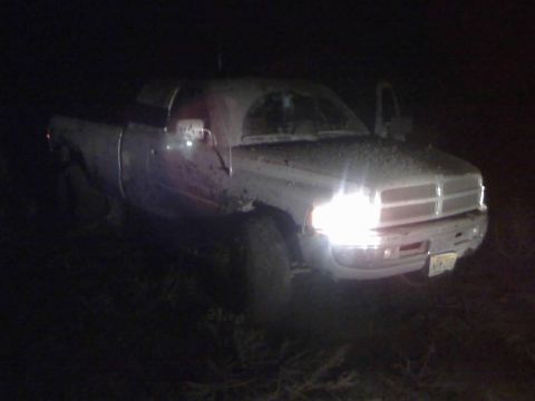 1996 Dodge 1500 - A white pickup truck is parked outdoors at night with its headlights illuminated and driver's door illuminated.