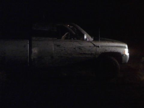 1996 Dodge 1500 - A muddy 1996 Dodge 1500 pickup truck is seen from the front-three-quarter angle in the dark.