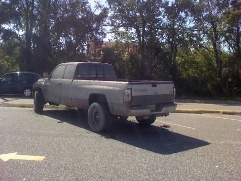 1996 Dodge 1500 - This Dodge Ram pickup truck is parked on asphalt with trees in the background.