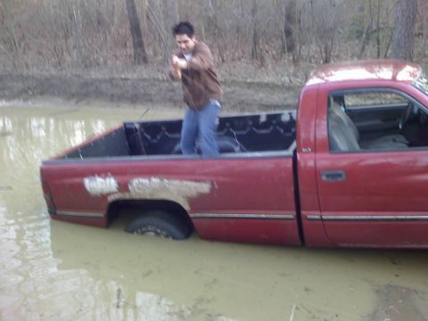 1996 Dodge 1500 - This 1996 Dodge 1500 is stuck deep in the mud with a person standing in the truck bed.