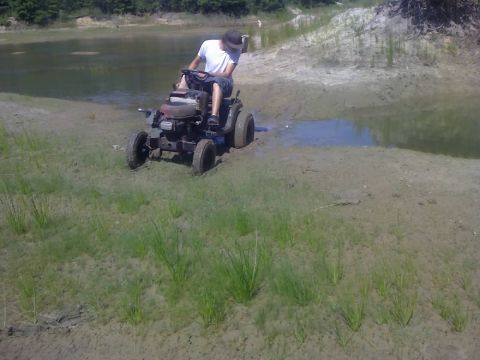 1996 Dodge 1500 - Riding mower stuck in mud near a body of water with a person on it.