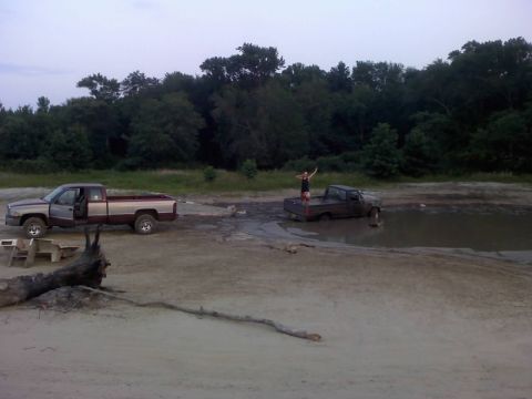1996 Dodge 1500 - Two pickup trucks are stuck in a muddy area, with people standing on top of them.