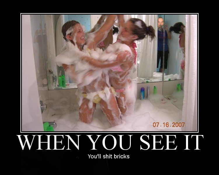 Two women in a shower covered in soap suds, with a man reflected in the mirror.