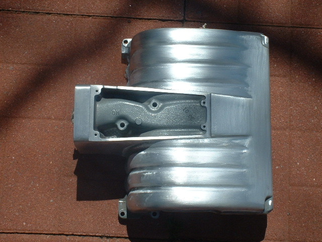 Bare-metal cast aluminum housing or cover laid on a red brick surface