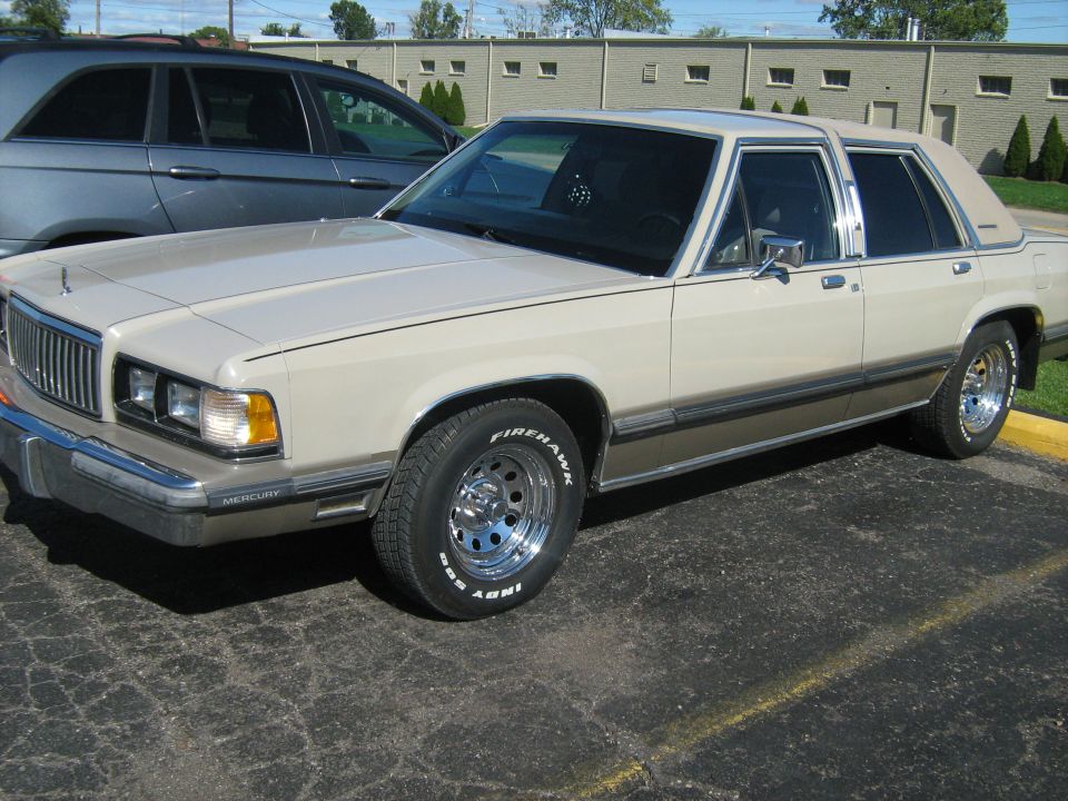 Tan Mercury sedan parked in a lot, three-quarter front view with chrome wheels