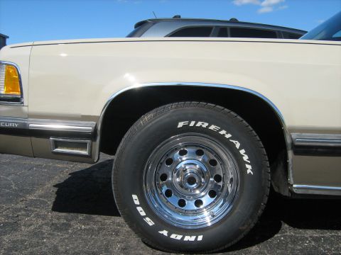 1988 Mercury Grand Marquis - Close-up of the side of a 1988 Mercury Grand Marquis, showing the fender and wheel.