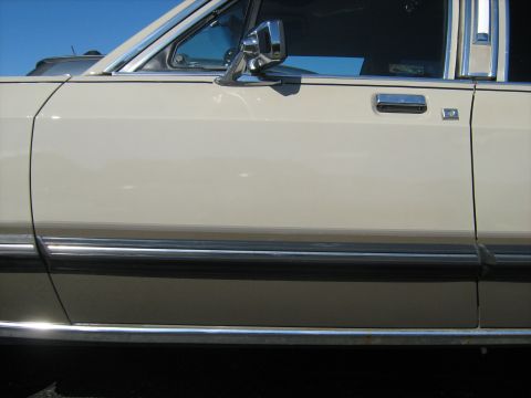 1988 Mercury Grand Marquis - Close-up of a car's side panel, highlighting its door handle and trim details.
