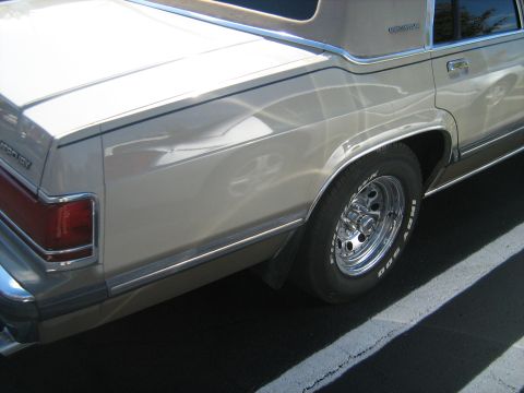 1988 Mercury Grand Marquis - The rear of a tan Mercury Grand Marquis is shown, highlighting its chrome trim and alloy wheels.