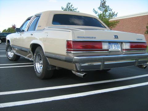 1988 Mercury Grand Marquis - Rear view of a tan 1988 Mercury Grand Marquis parked in a lot with white lines.