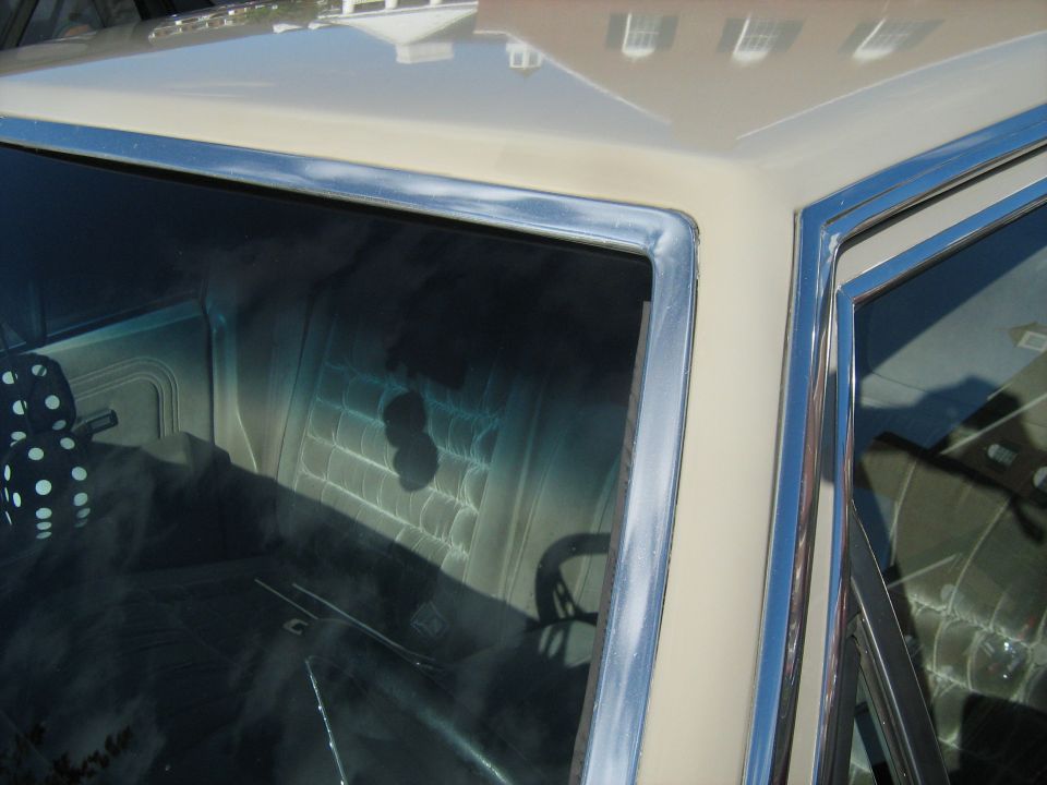 Close-up of car's roofline and interior, showing patterned seat and steering wheel reflection