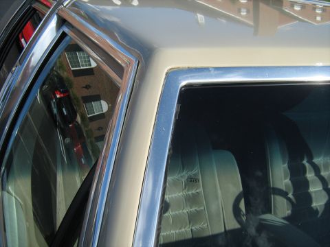 1988 Mercury Grand Marquis - Close-up view of a car's interior and exterior trim, with a reflection of a building in the window.