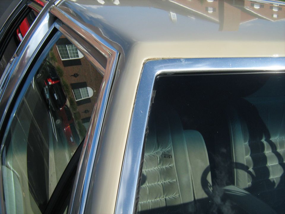Car interior with quilted seats and chrome trim on the exterior. Reflection shows a brick building