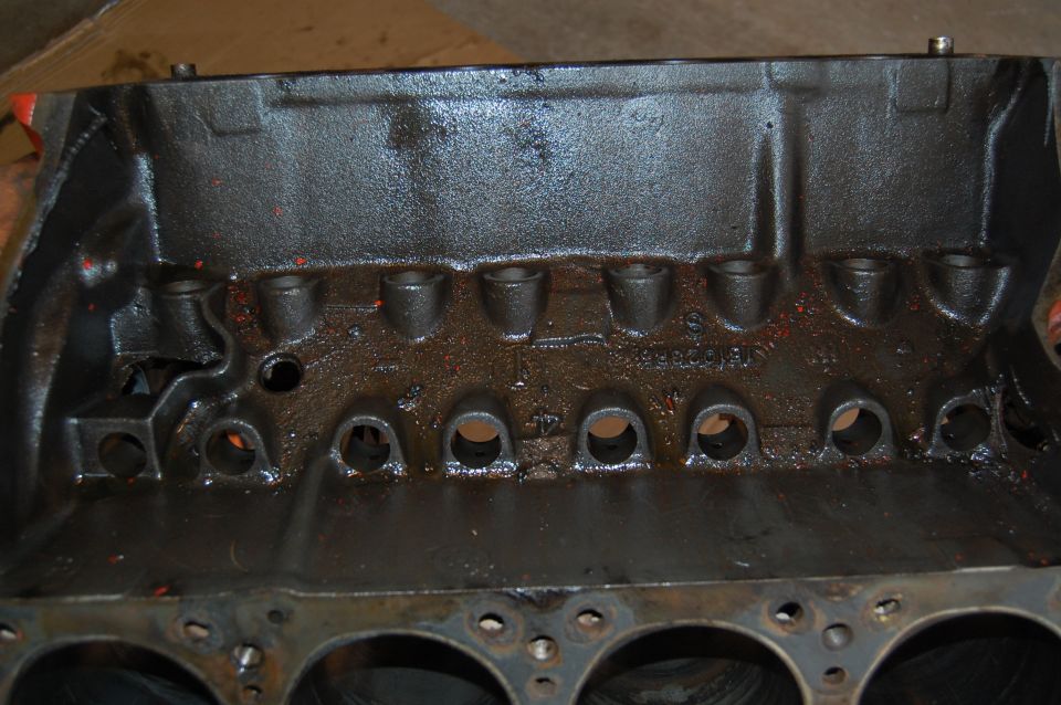 Close-up of a black engine block with oil residue. Cylinders are visible